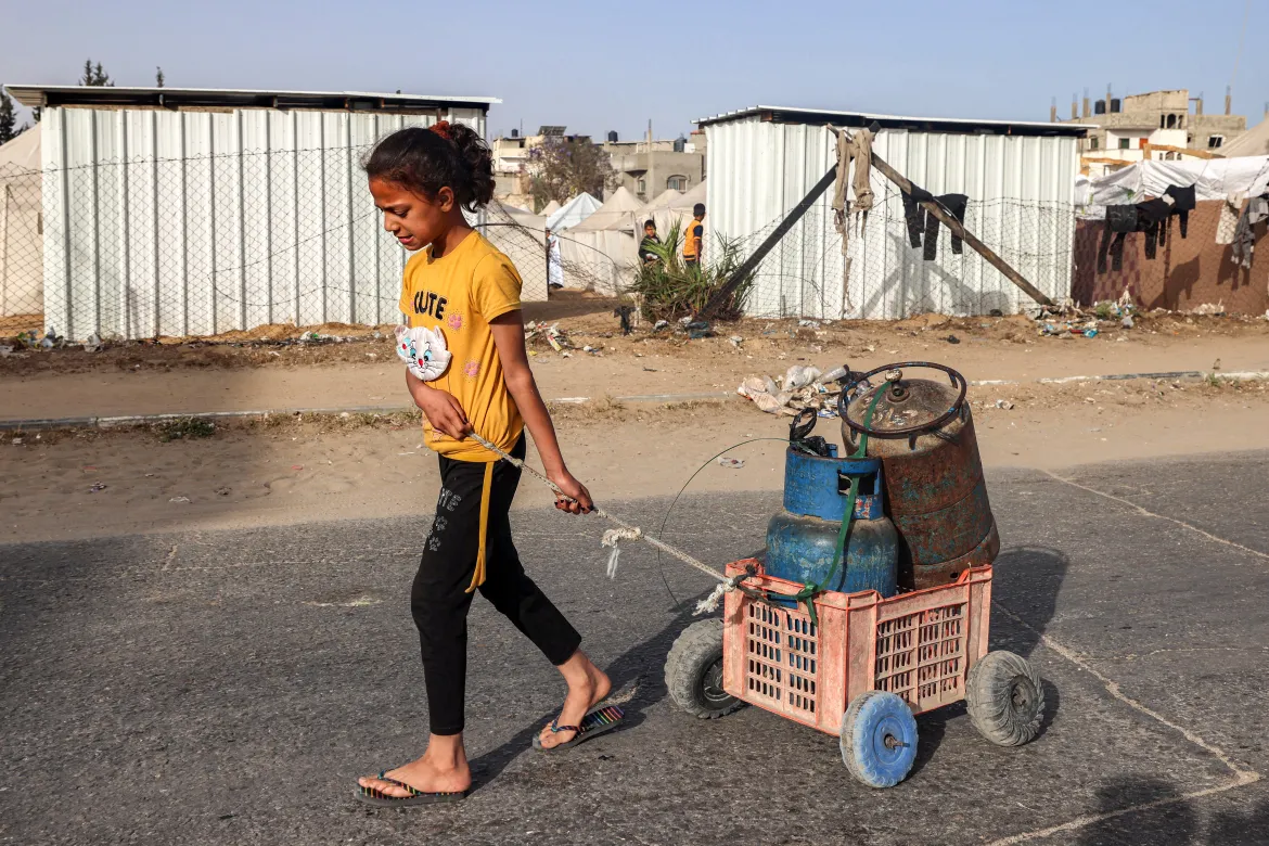 A girl pulls a cart loaded with gas cylinders along a street in Rafah in the southern Gaza Strip.